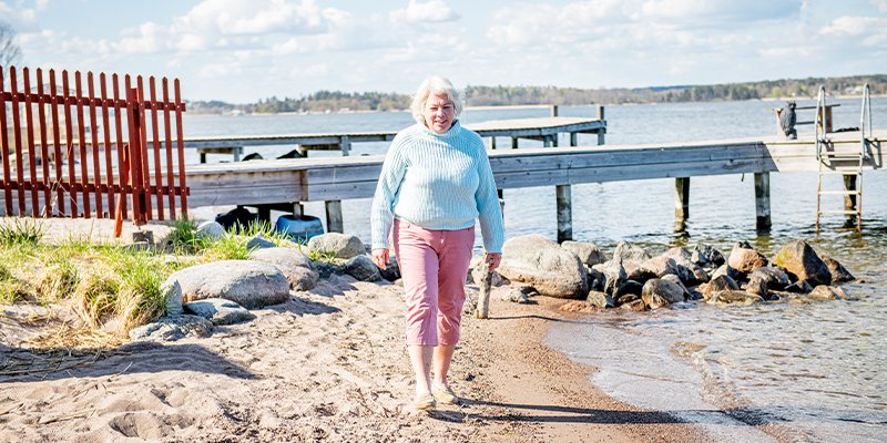 Anne Sophie har rosa byxor och en blå tröja och går på en strand.
