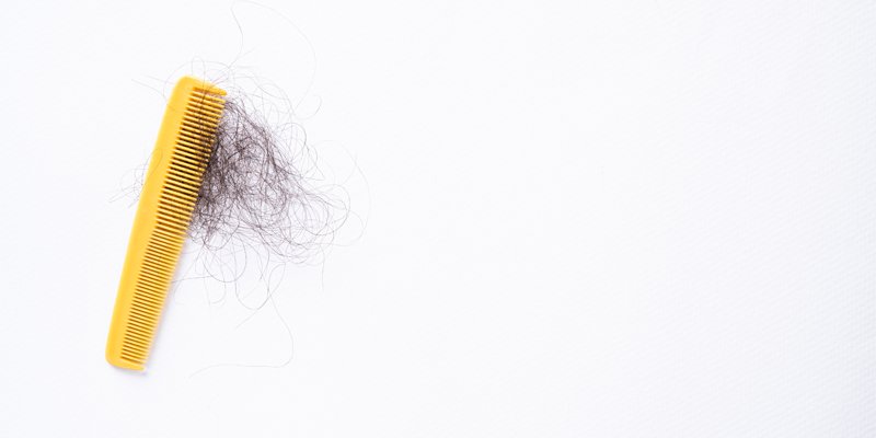 en gul kamm med mörka hårstrån